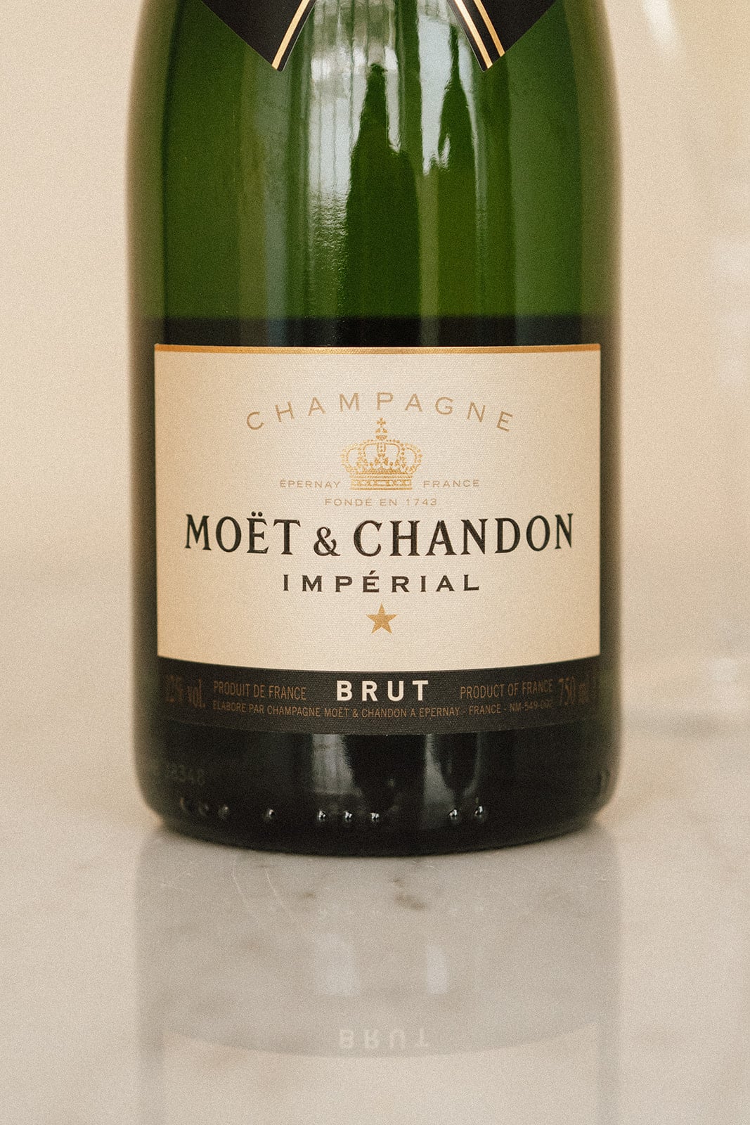 Bouteille de champagne Moët & Chandon sur une surface claire. Étiquette indiquant