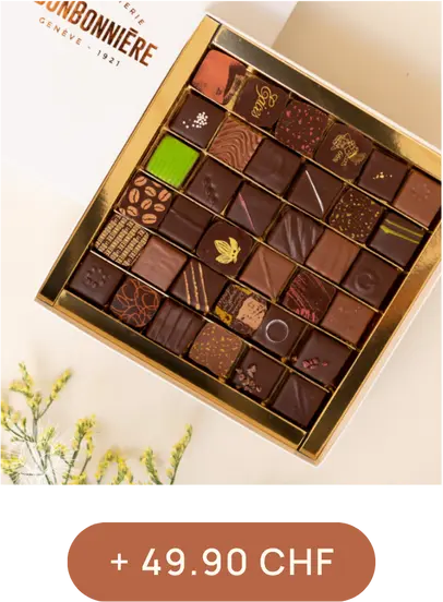 Boîte de chocolats assortis en gros plan, disposée dans une écrin doré, estampillé "La Bonbonnière Genève 1921", avec un prix en bas indiquant "+ 49.90 CHF".